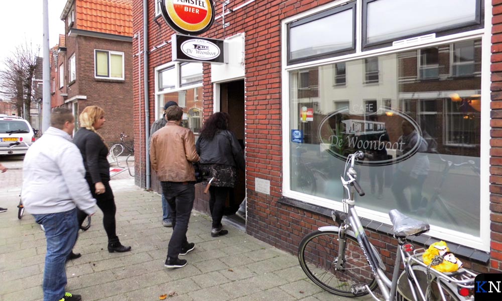 Figuranten lopen café De Woonboot in op aanwijzingen van de regisseur.