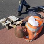 Een Griekse werknemer werkt aan de steunen voor de nieuwe rijstrookafscheiding.